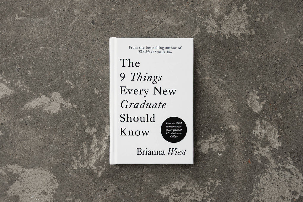 Book titled 'The 9 Things Every New Graduate Should Know' by Brianna Wiest on a textured gray surface