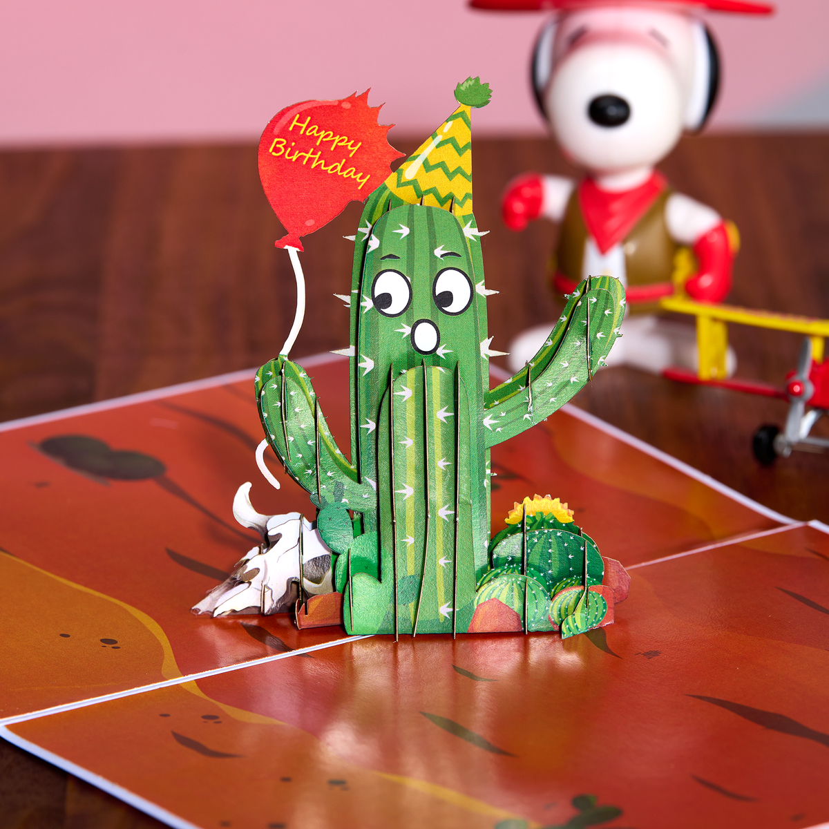 3D paper cactus with a 'Happy Birthday' balloon on a wooden surface.