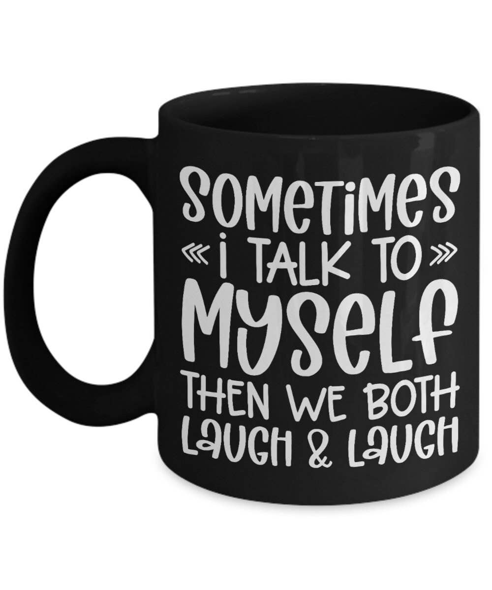A black ceramic coffee mug with white printed text that reads 'SOMETIMES I TALK TO MYSELF THEN WE BOTH LAUGH & LAUGH' on a plain white background.
