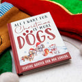Book titled 'All I Want for Christmas is More Dogs' with festive design on a soft fabric background.