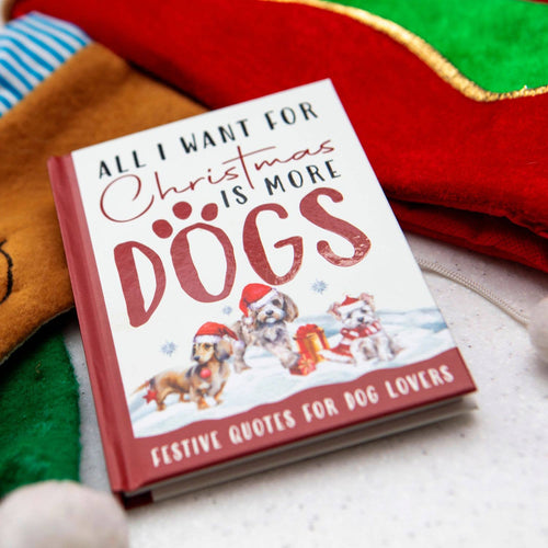 Book titled 'All I Want for Christmas is More Dogs' with festive design on a soft fabric background.
