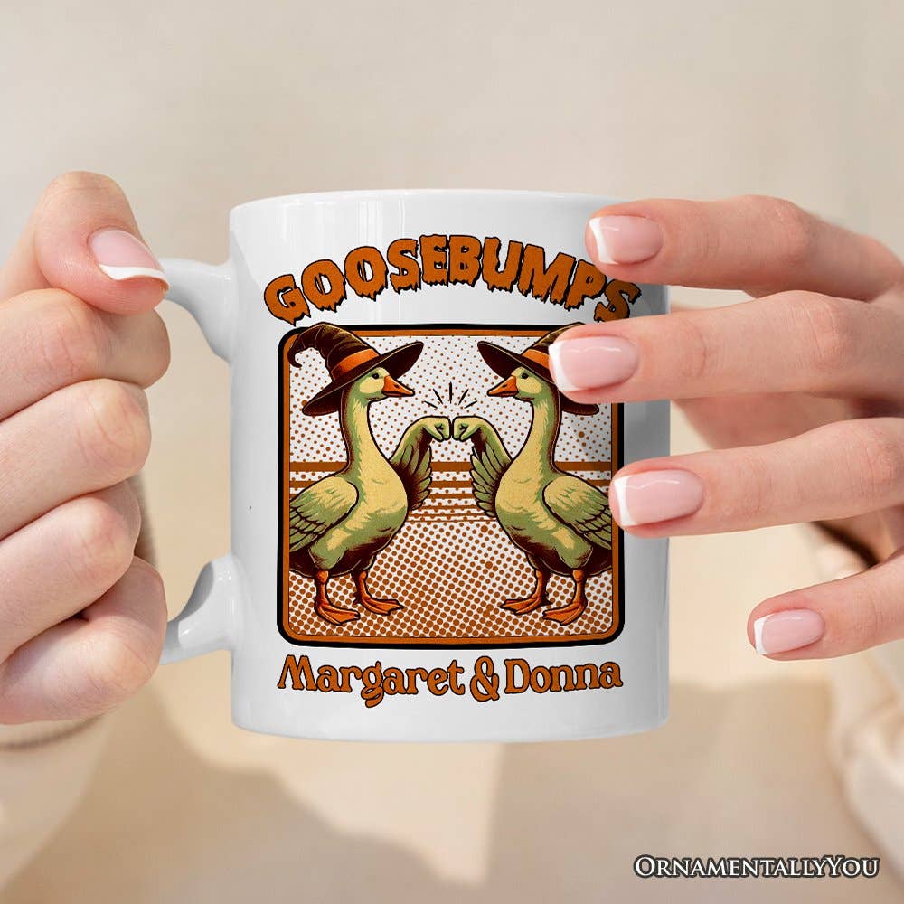 Mug with cartoon ducks and 'Goosebumps' text held by a person against a beige background