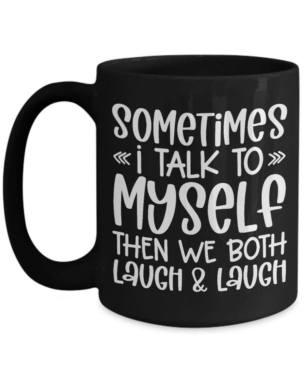 A black ceramic coffee mug with white text that reads 'SOMETIMES I TALK TO MYSELF THEN WE BOTH LAUGH & LAUGH' on a plain white background.