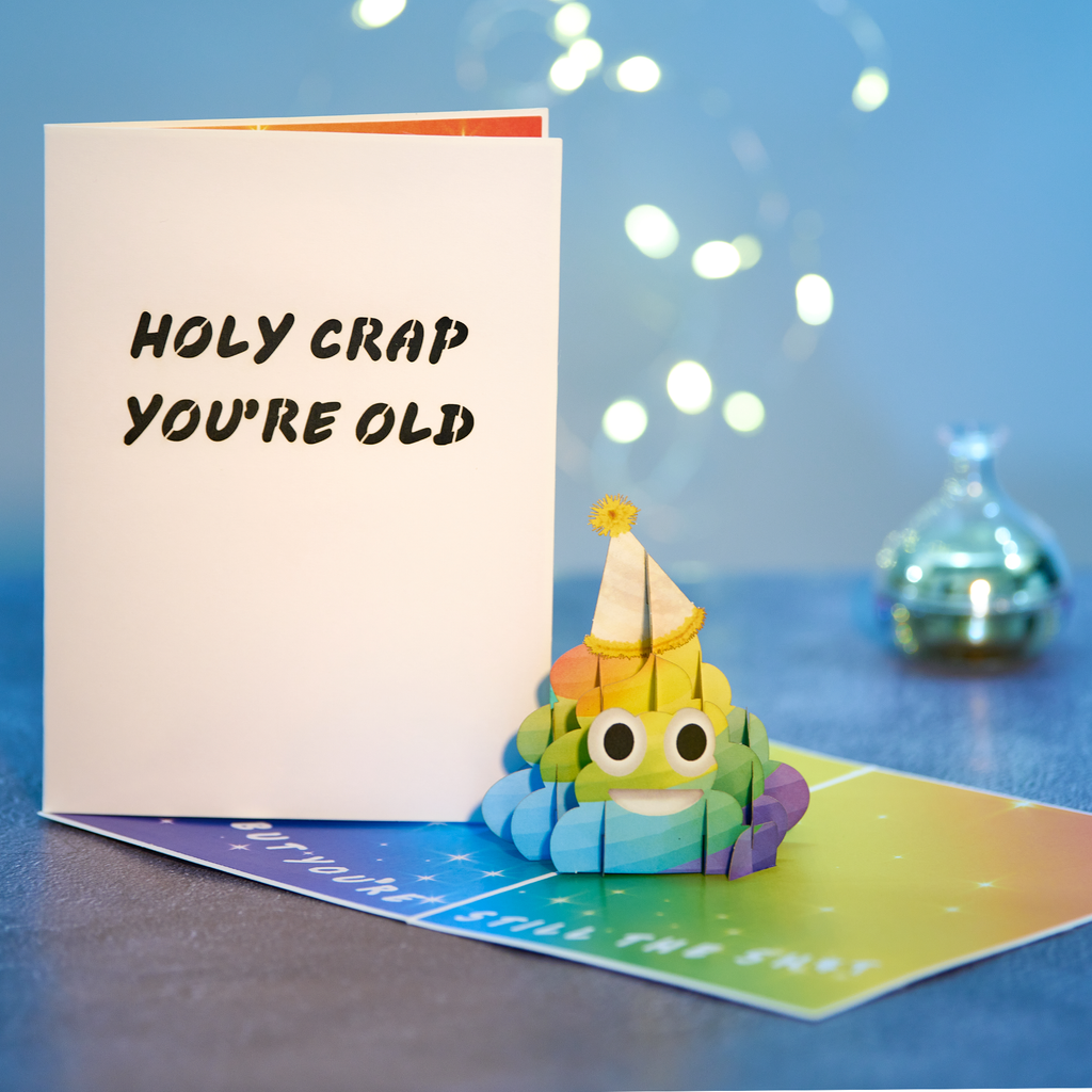 Colorful paper craft figure with a birthday hat next to a card with text on a blue background
