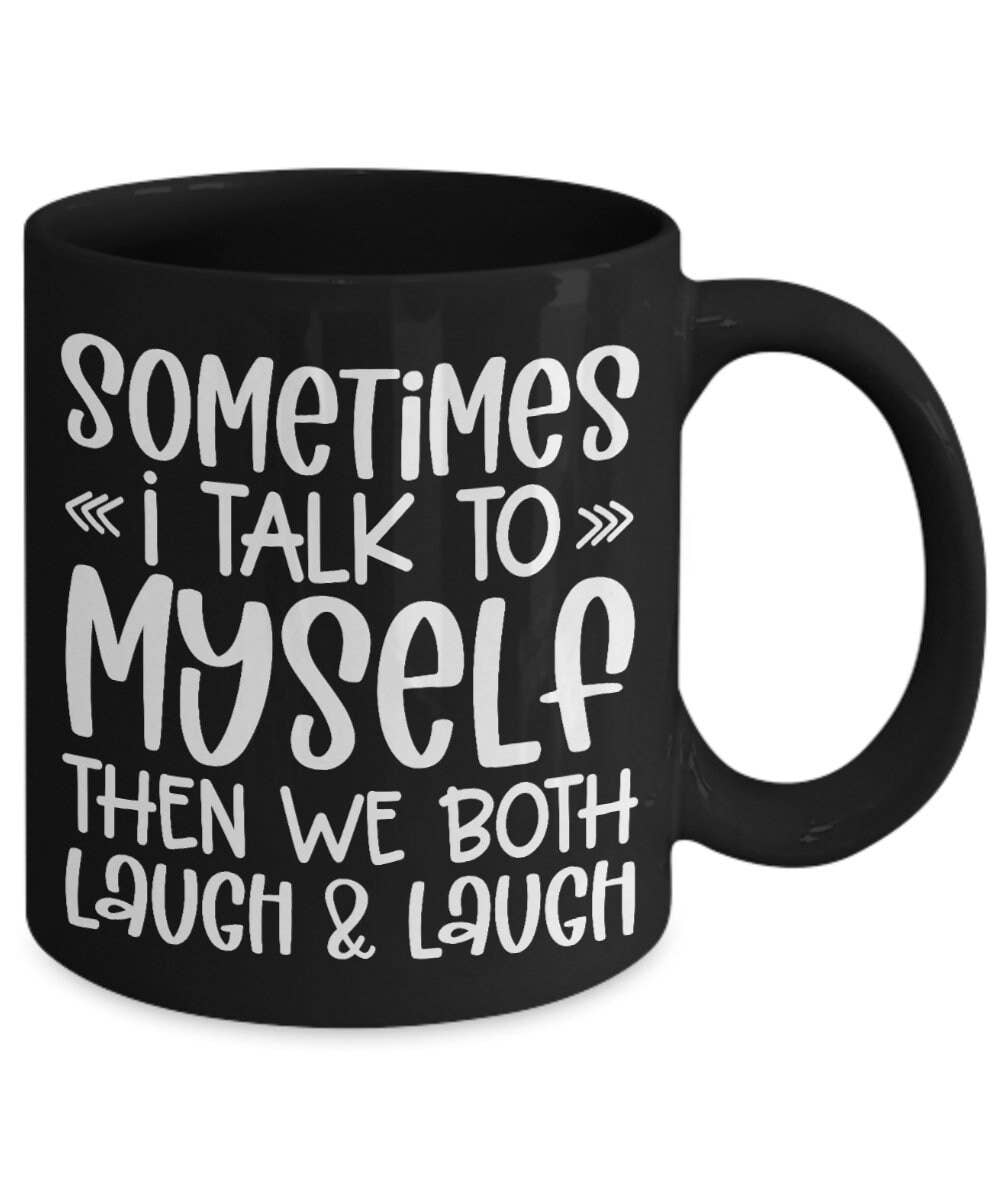A black ceramic coffee mug with white hand-drawn style text that reads, 'SOMETIMES I TALK TO MYSELF THEN WE BOTH LAUGH & LAUGH' on a plain white background.