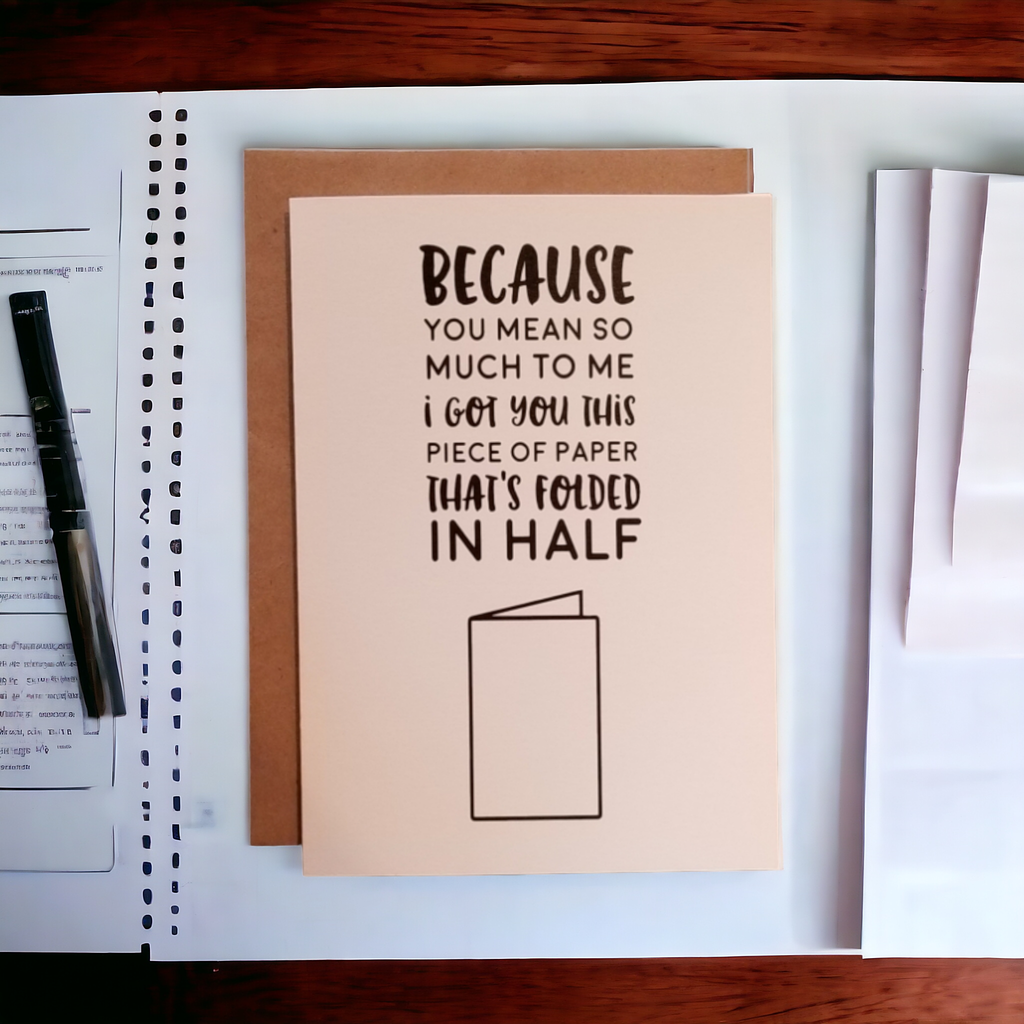 Card with humorous message on a desk with a pen and paper.