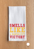 White towel with 'Smells Like a Kansas City Victory' text on a wooden surface