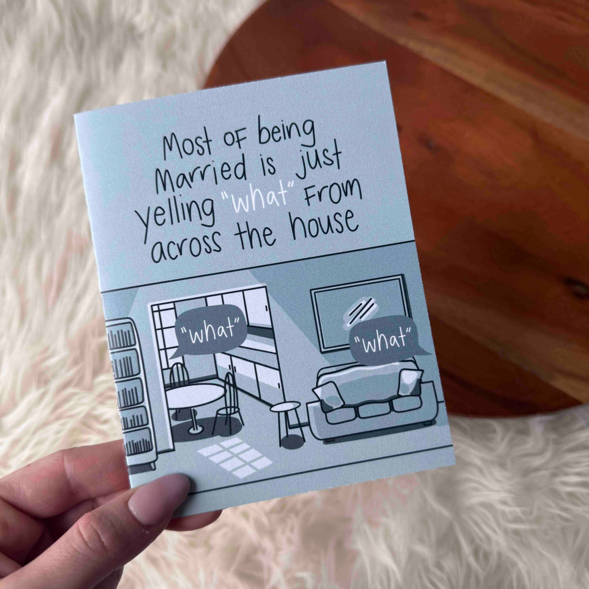 Note with humorous text about married life held over a living room illustration.