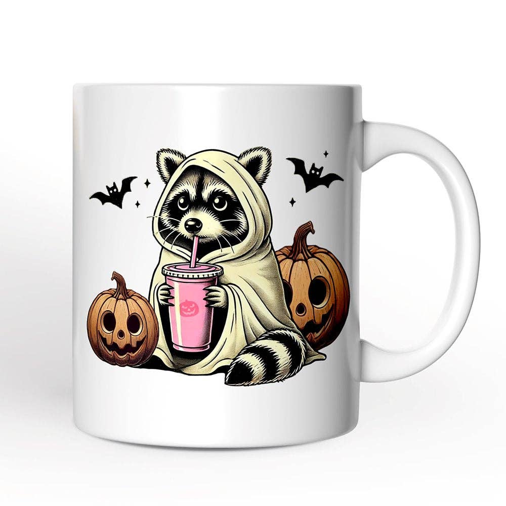 Mug with a raccoon in a hoodie drinking from a pink cup, surrounded by pumpkins and bats on a white background.