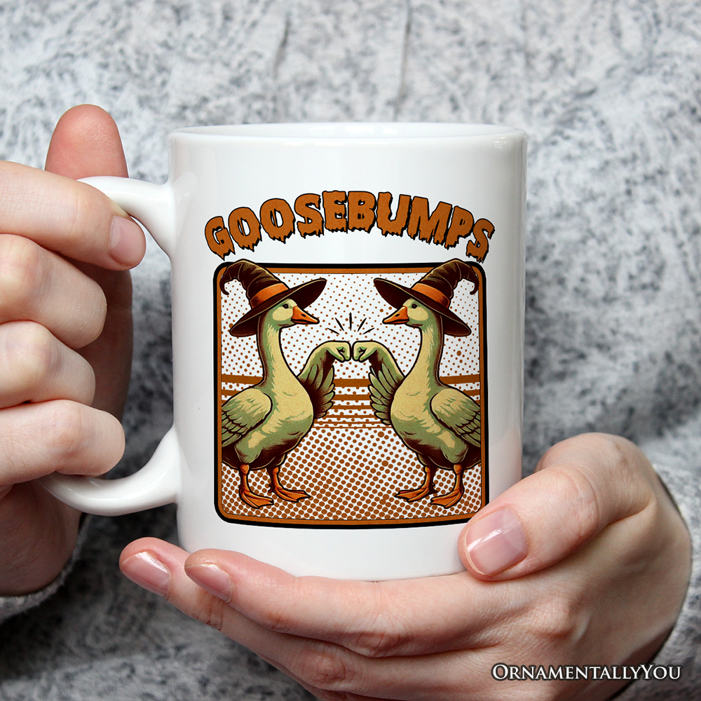 White mug with 'GOOSEBUMPS' design featuring ducks and a witch hat, held by hands against a gray background.