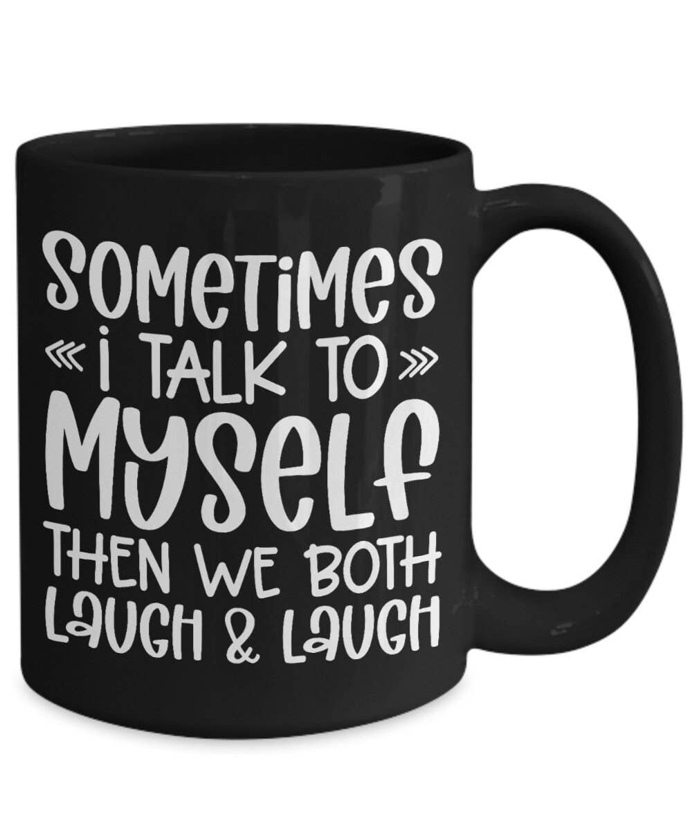 A black ceramic mug with white printed text that reads, 'SOMETIMES I TALK TO MYSELF THEN WE BOTH LAUGH & LAUGH' on a plain white background.