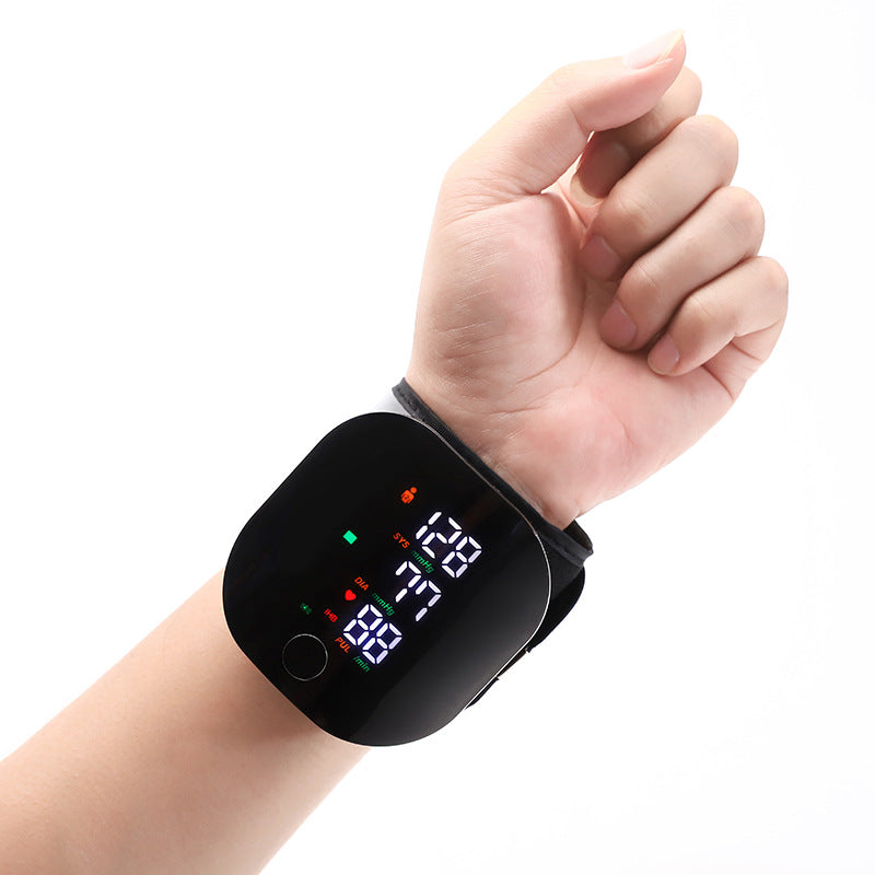 Hand wearing a digital blood pressure monitor on a white background