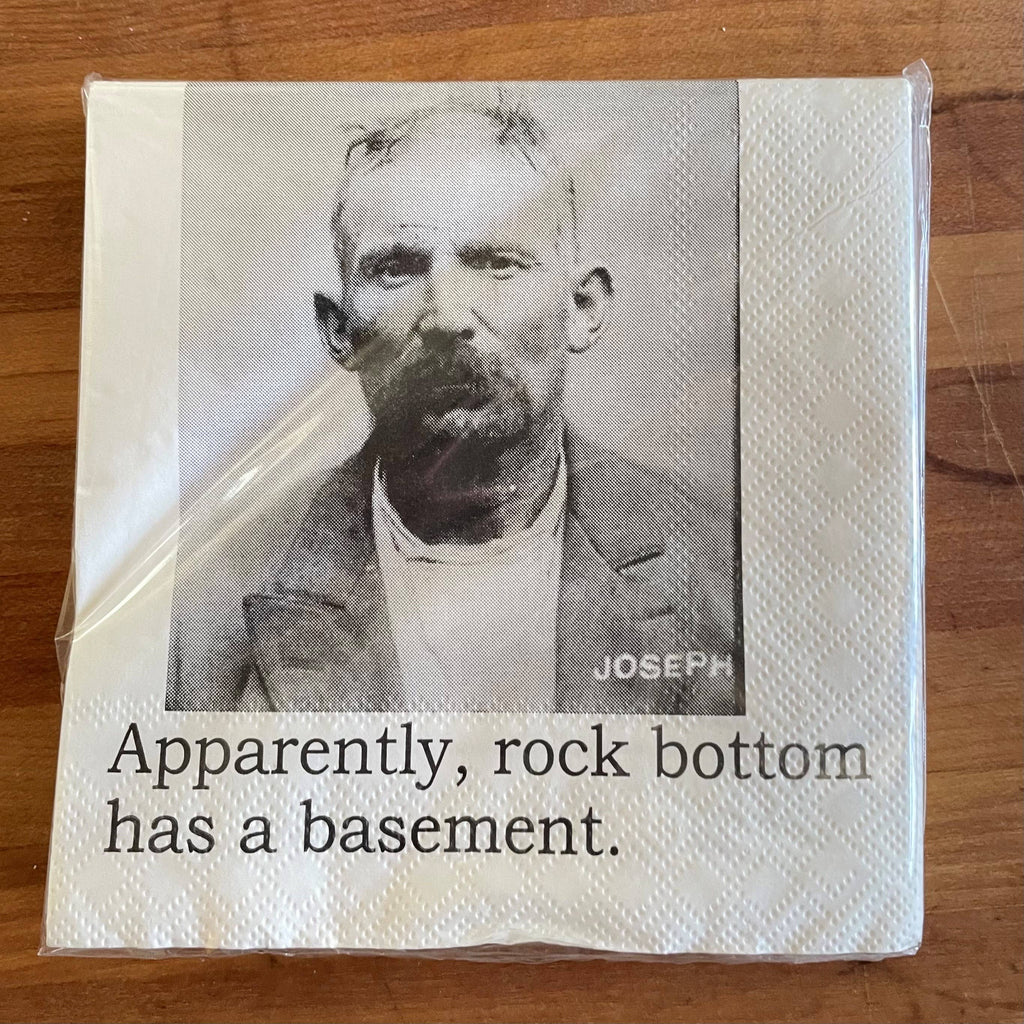 Napkin with a black and white photo of a man and humorous text on a wooden surface