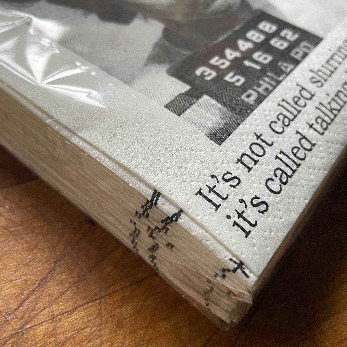 Stack of white napkins with black text on a wooden surface