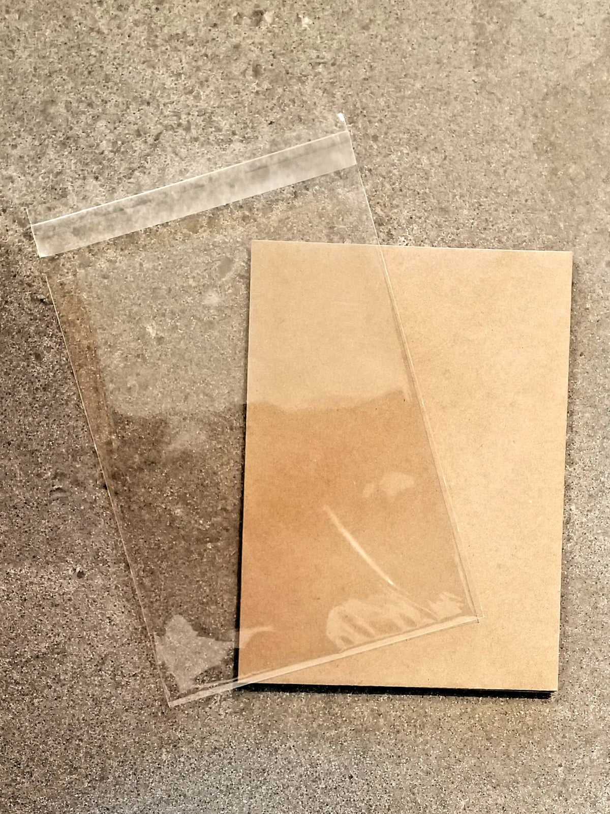 Clear plastic sheet and brown cardboard on a concrete surface