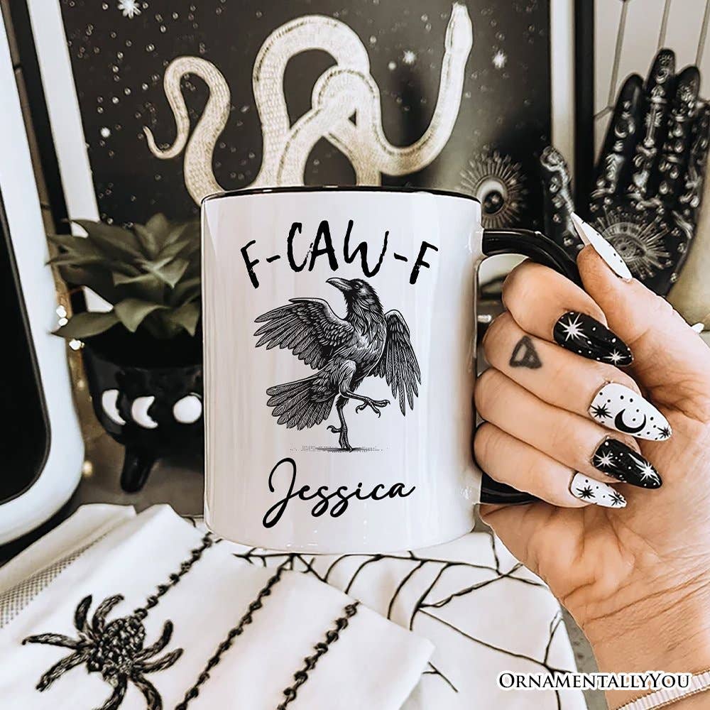 Mug with a bird design and text held by a hand with decorative nails, against a dark background with decorative elements.