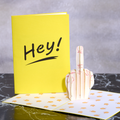 Yellow card with 'Hey!' text and a 3D hand gesture card on a gray surface.